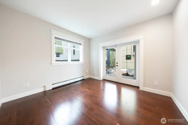 an empty room with wooden floor and windows
