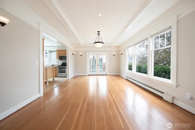 a view of an empty room with a window and wooden floor