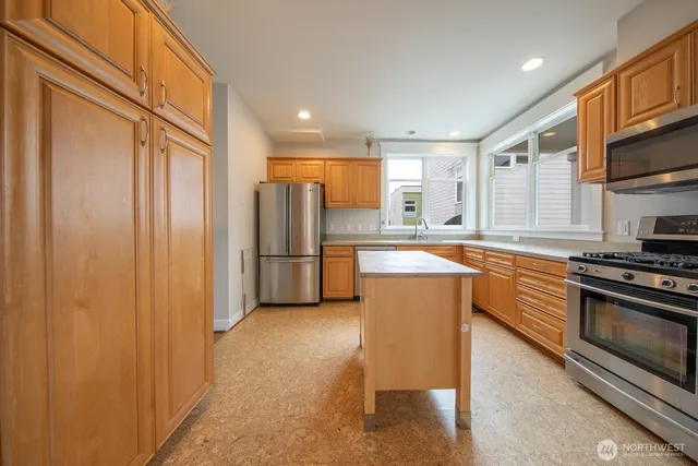 a large kitchen with stainless steel appliances granite countertop a refrigerator and a stove top oven