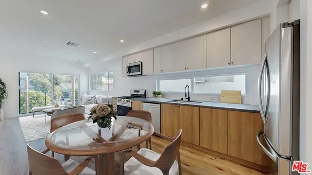 a kitchen with stainless steel appliances granite countertop a refrigerator a sink a stove and island with wooden floor