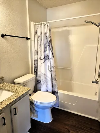 a bathroom with a granite countertop bathtub shower sink vanity and toilet
