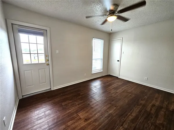 an empty room with wooden floor chandelier fan and windows