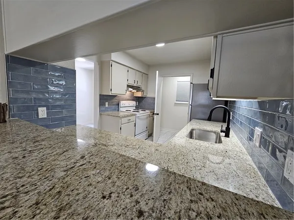 a kitchen with granite countertop a stove and cabinets