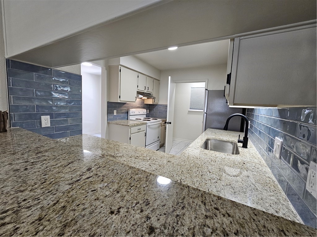 4816 Delwood Street, Unit 4 Corpus Christi, TX 78413 - Photo 5 of 22 a kitchen with granite countertop a stove and cabinets