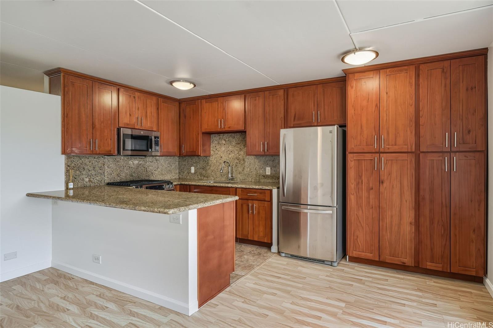 910 Ahana Street, Unit 308 Honolulu, HI 96814 - Photo 7 of 20 a kitchen with stainless steel appliances granite countertop a refrigerator a stove and a sink with wooden floors