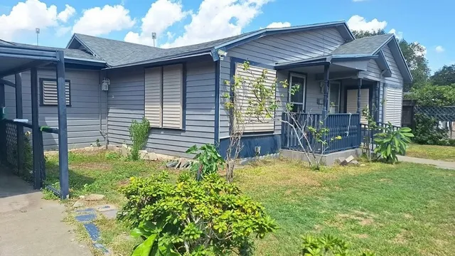 a view of a house with brick walls and a yard with plants