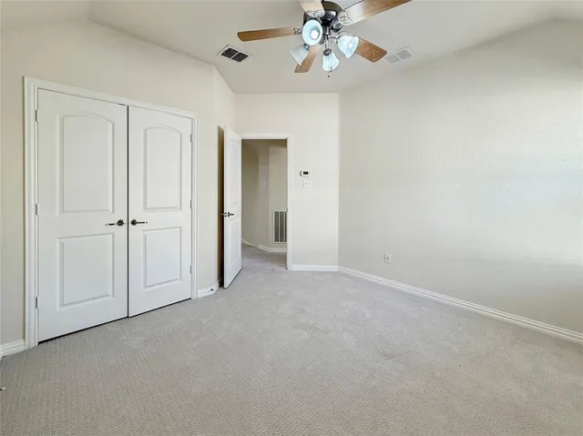 an empty room with windows and fan chandelier fan