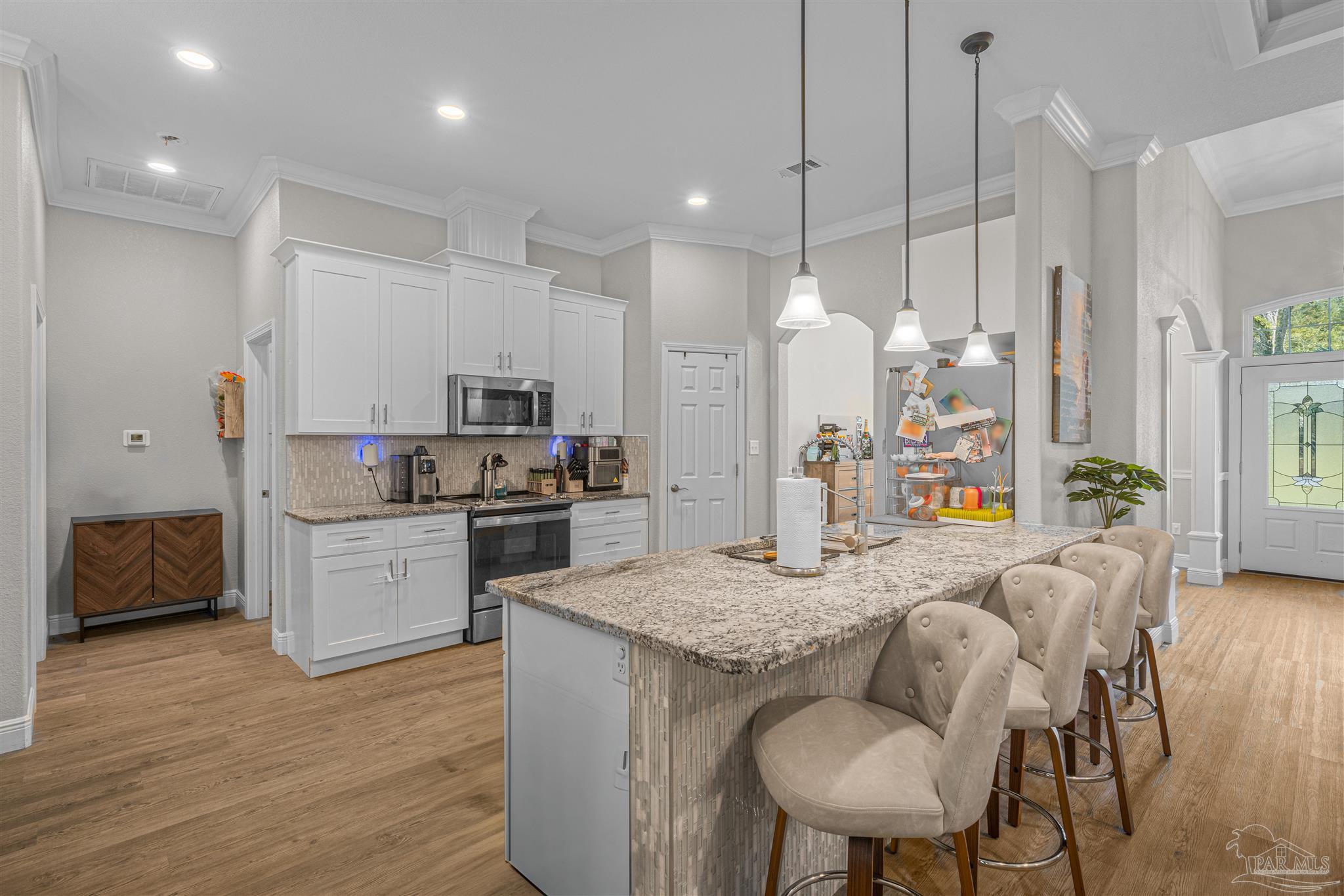 6245 Muldoon Road Pensacola, FL 32526 - Photo 12 of 44 a kitchen with kitchen island granite countertop a stove a sink a refrigerator and white cabinets with wooden floor