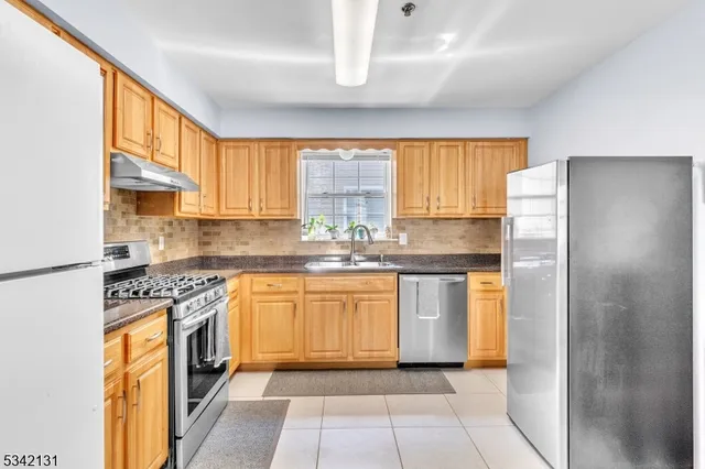 a kitchen with stainless steel appliances granite countertop a refrigerator sink and stove