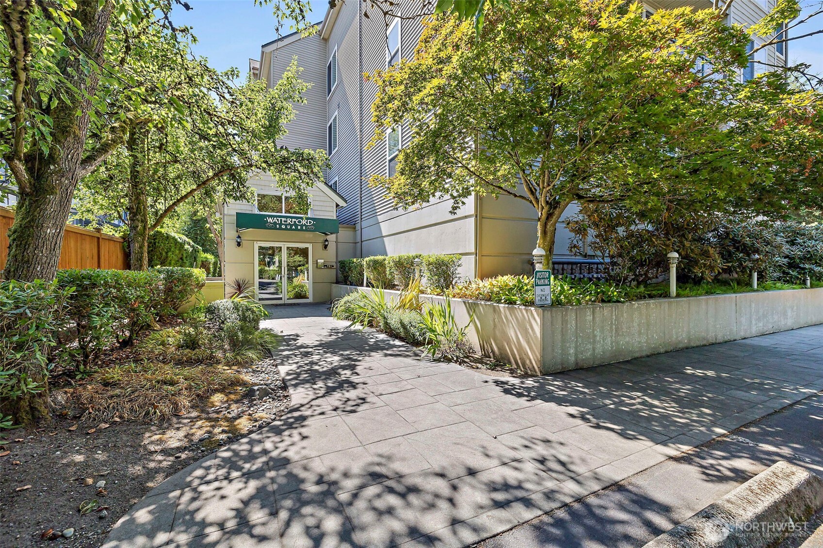 6831 Northeast 170th Street, Unit 306 Kenmore, WA 98028 - Photo 1 of 32 a view of a house with a small yard and large tree