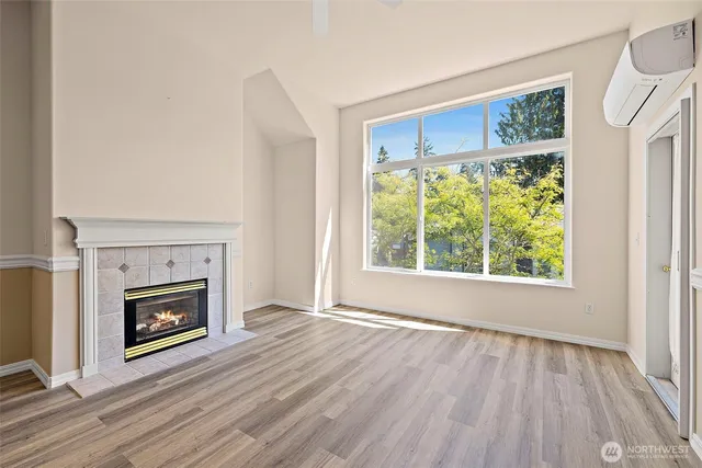 a view of an empty room with wooden floor fireplace and a window