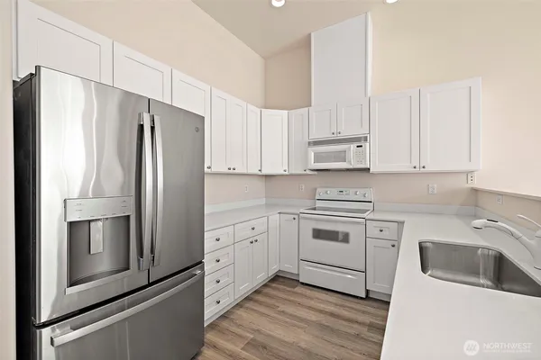 a kitchen with granite countertop white cabinets and stainless steel appliances