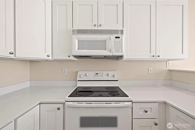a kitchen with white cabinets and white appliances