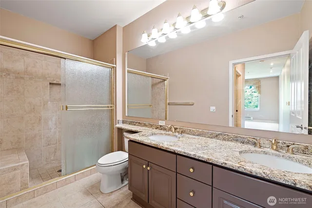 a bathroom with a granite countertop sink toilet a large mirror a shower and vanity