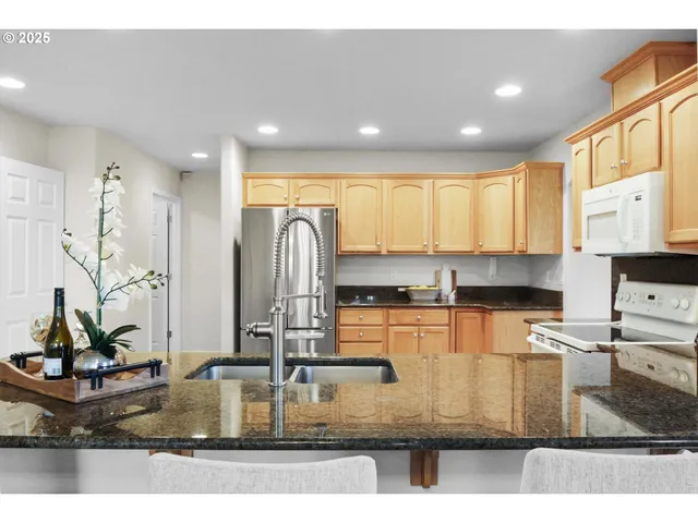 a kitchen with kitchen island granite countertop a stove a sink a refrigerator and a counter top space