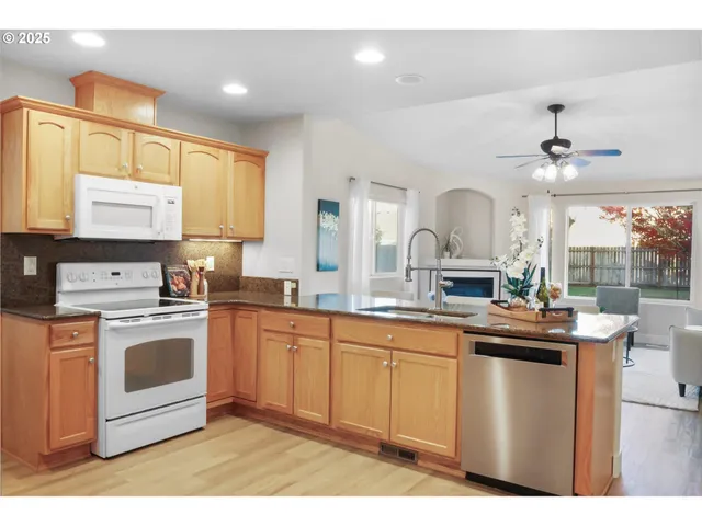 a kitchen with stainless steel appliances a sink a stove a refrigerator cabinets and a window