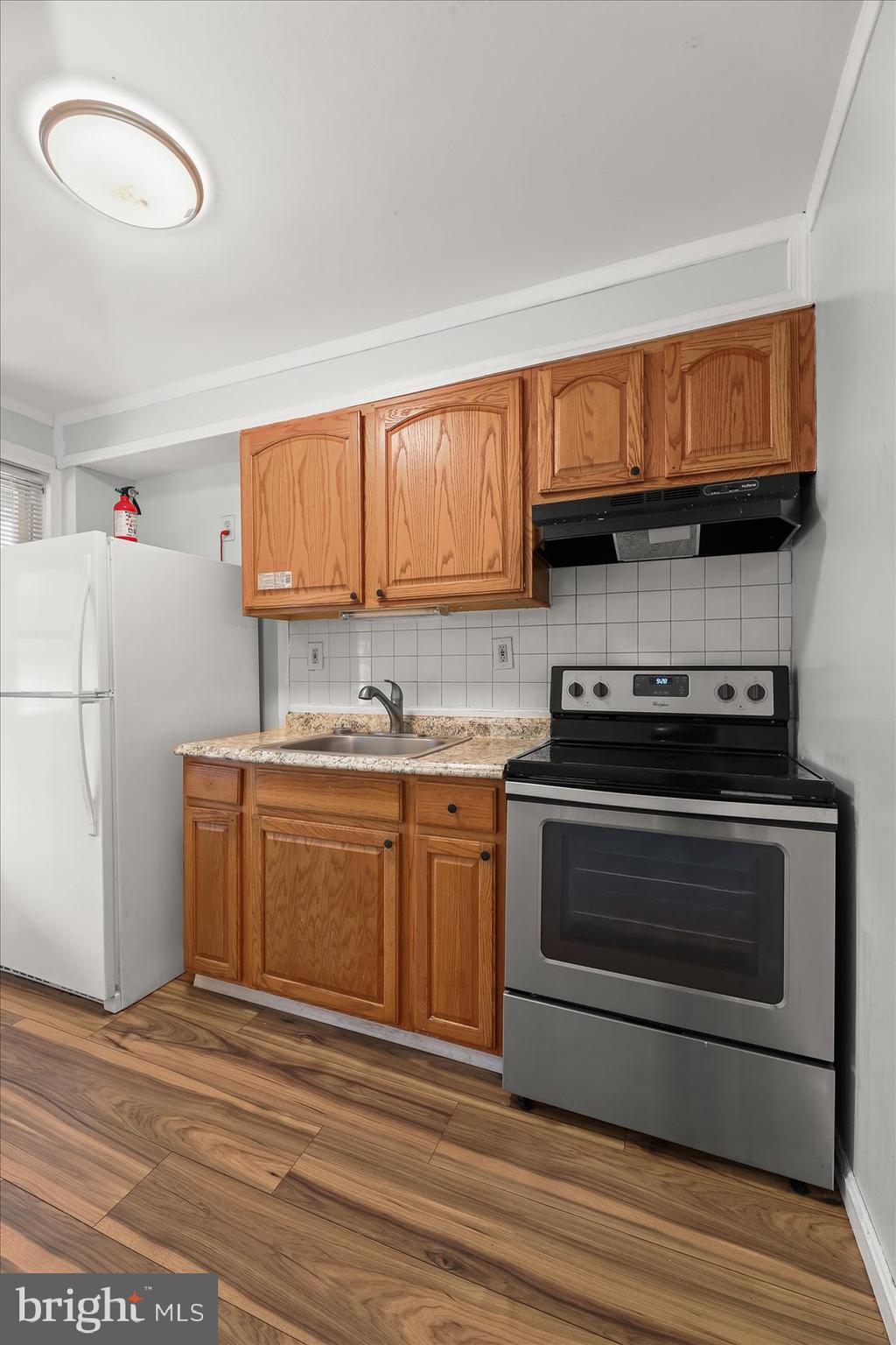 3720 St Victor Street Baltimore, MD 21225 - Photo 15 of 41 a kitchen with granite countertop a stove top oven a sink and a microwave