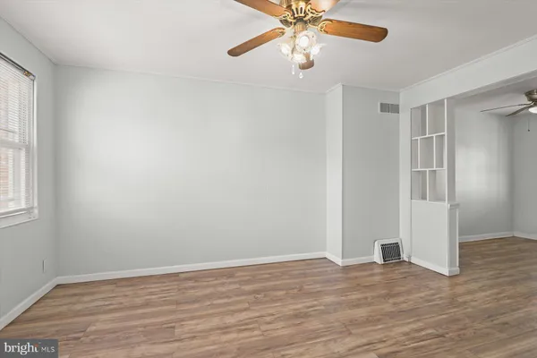 an empty room with wooden floor chandelier fan and windows