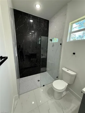 a bathroom with a toilet and a glass door shower