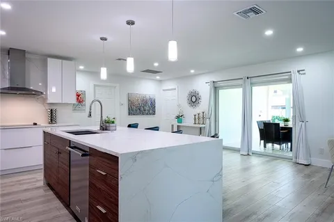 a kitchen with kitchen island a stove a sink and white cabinets