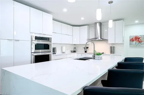 a kitchen with kitchen island stainless steel appliances a table chairs refrigerator and microwave