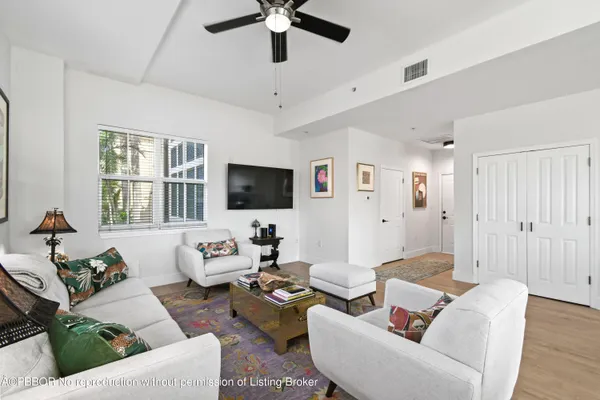 a living room with couches and kitchen view with a large window