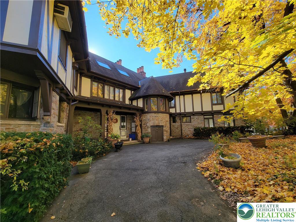 444 West 3rd Street, Unit 9 Bethlehem, PA 18015 - Photo 1 of 16 A winding asphalt driveway leads to a distinguished residence, framed by vibrant autumn foliage and mature landscaping.