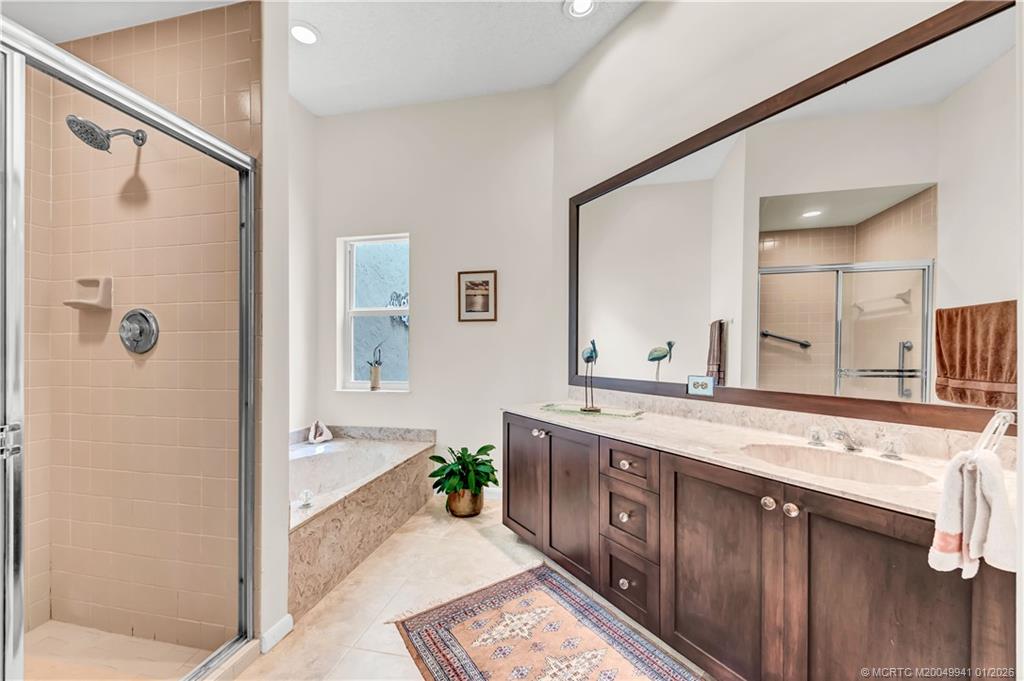 2437 Southwest Foxpoint Trail Palm City, FL 34990 - Photo 20 of 32 a spacious bathroom with a granite countertop tub sink a mirror and a shower