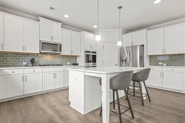 a kitchen with stainless steel appliances granite countertop a white cabinets and wooden floor