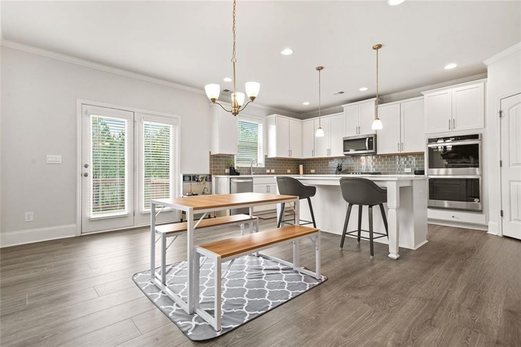1606 Chancery Lane Lithia Springs, GA 30122 - Photo 14 of 66 a kitchen with stainless steel appliances granite countertop a stove top oven a refrigerator a sink and a dining table with wooden floor