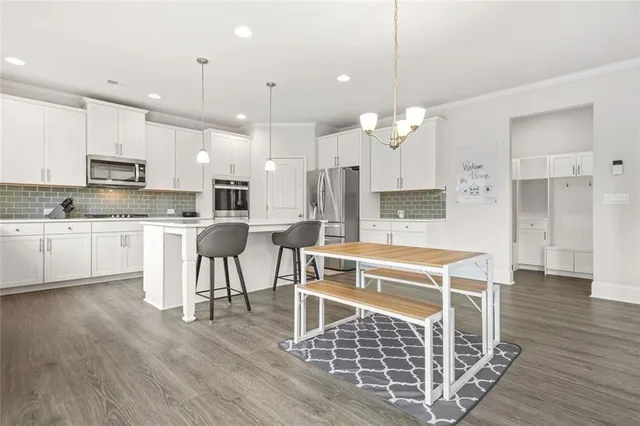 a large kitchen with kitchen island granite countertop a stove a sink a refrigerator and white cabinets with wooden floor