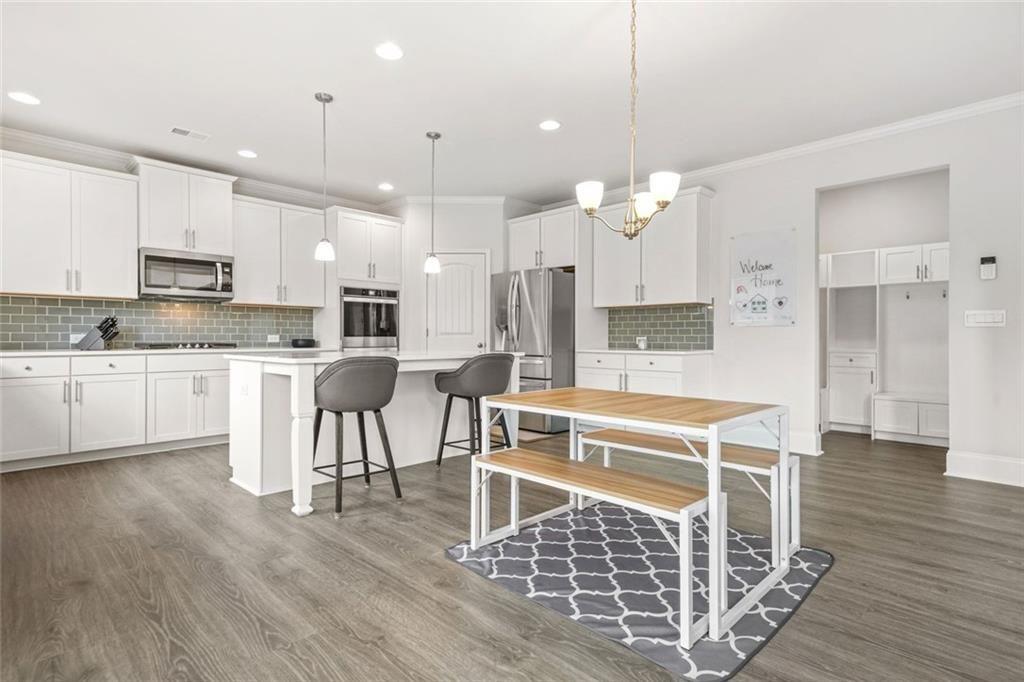 1606 Chancery Lane Lithia Springs, GA 30122 - Photo 16 of 66 a large kitchen with kitchen island granite countertop a stove a sink a refrigerator and white cabinets with wooden floor