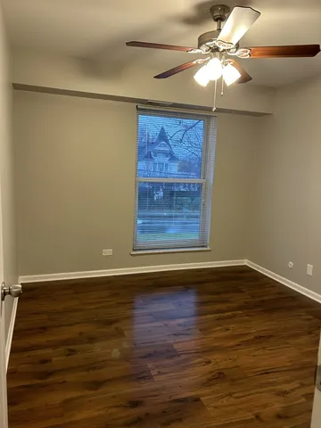 a view of an empty room with wooden floor and a chandelier fan