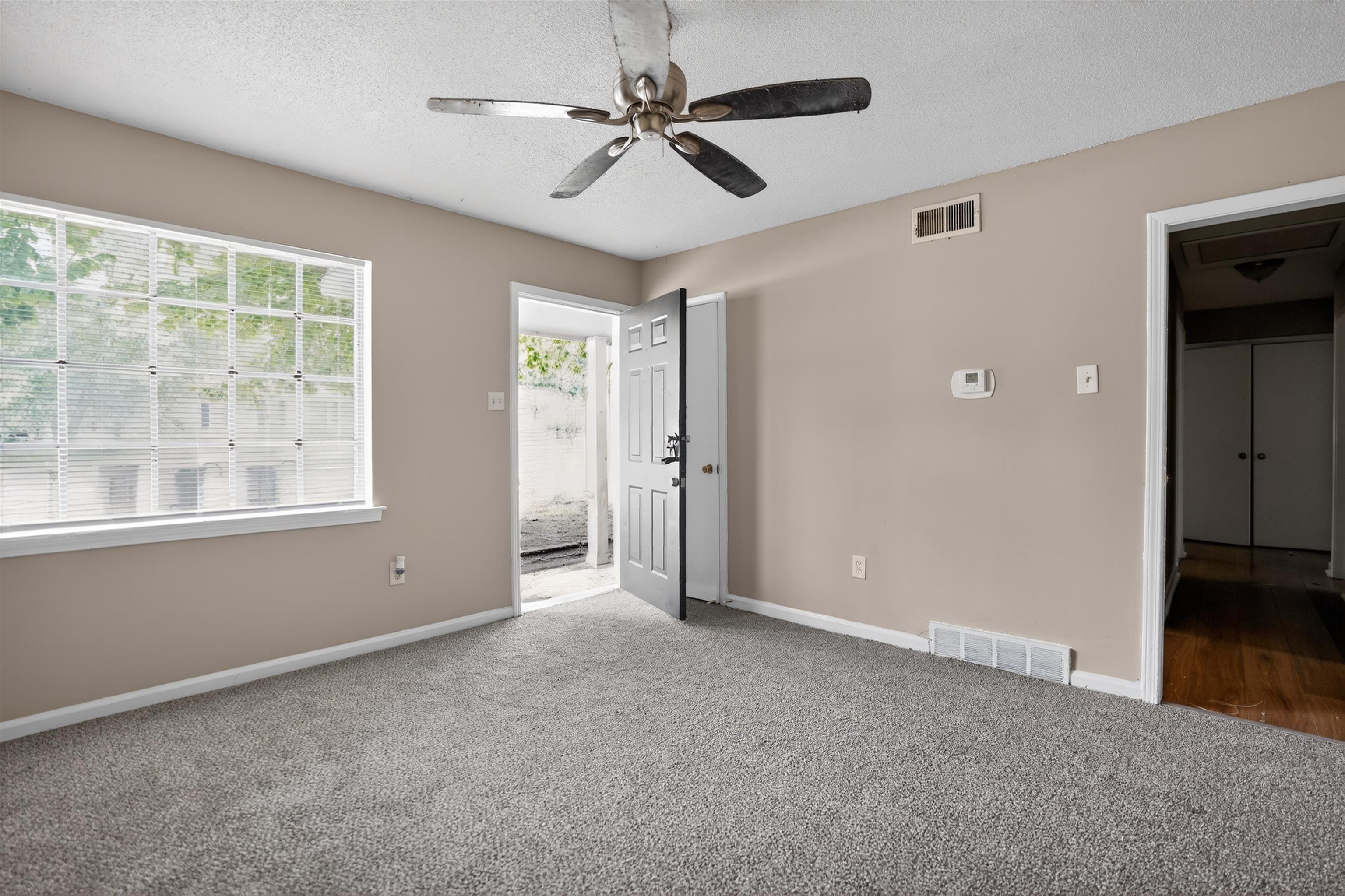 4530 Spring Valley Drive Memphis, TN 38128 - Photo 13 of 15 Room featuring light neutral wall paint, gray carpet flooring, a multi-pane window with blinds, and a paneled entry door
