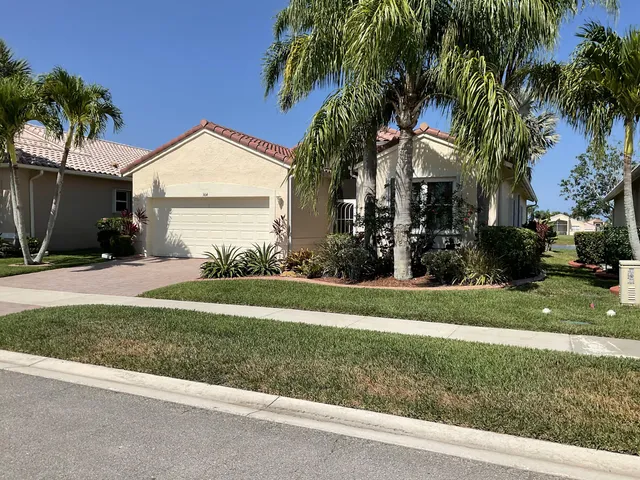 a view of a house with a yard and palm trees