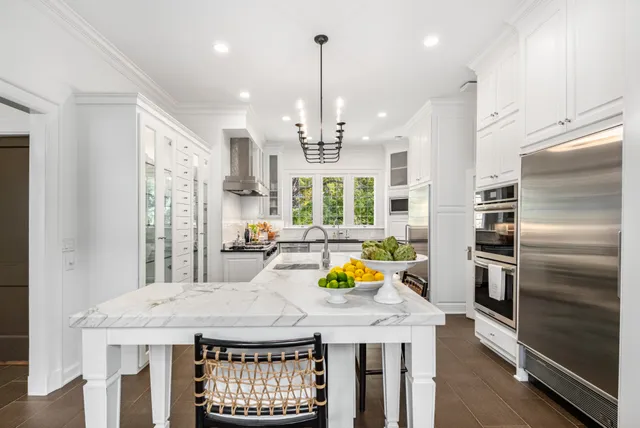 a kitchen with a refrigerator a stove a oven and a sink with wooden floor