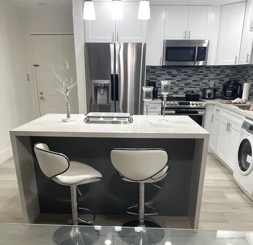 a kitchen with stainless steel appliances granite countertop a dining table chairs sink and cabinets