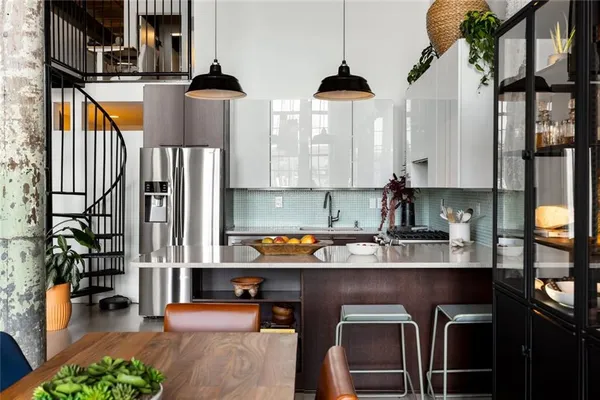 a kitchen with stainless steel appliances a refrigerator a sink a stove and white cabinets