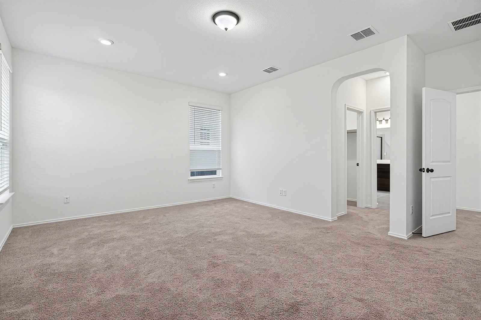 4600 Ercolano Lane Round Rock, TX 78665 - Photo 17 of 37 Spacious room featuring neutral carpet flooring, white walls, two windows with blinds, recessed lighting, and an arched entryway