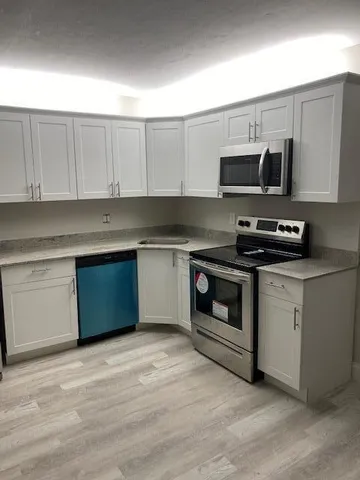 a kitchen with stainless steel appliances granite countertop a stove a sink and a microwave