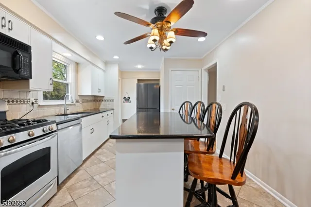 a kitchen with stainless steel appliances granite countertop a stove top oven a sink dishwasher a dining table and chairs with wooden floor