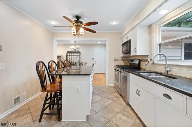 a kitchen with stainless steel appliances granite countertop a sink a stove a dining table and chairs