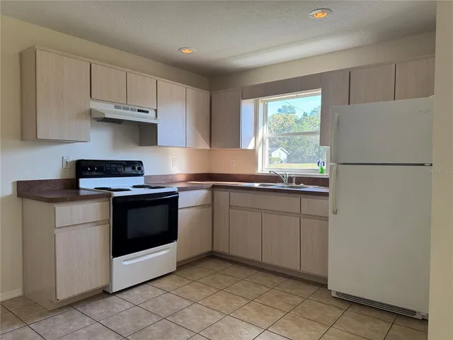 a kitchen with granite countertop cabinets stainless steel appliances and a window