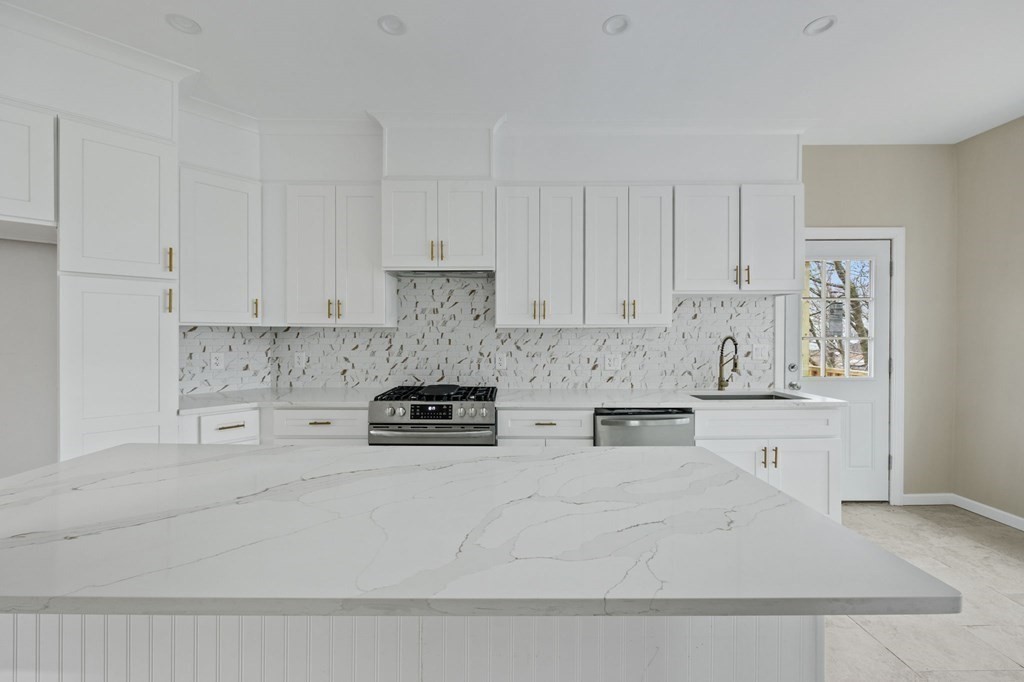 a kitchen with stainless steel appliances granite countertop a stove a white and white cabinets