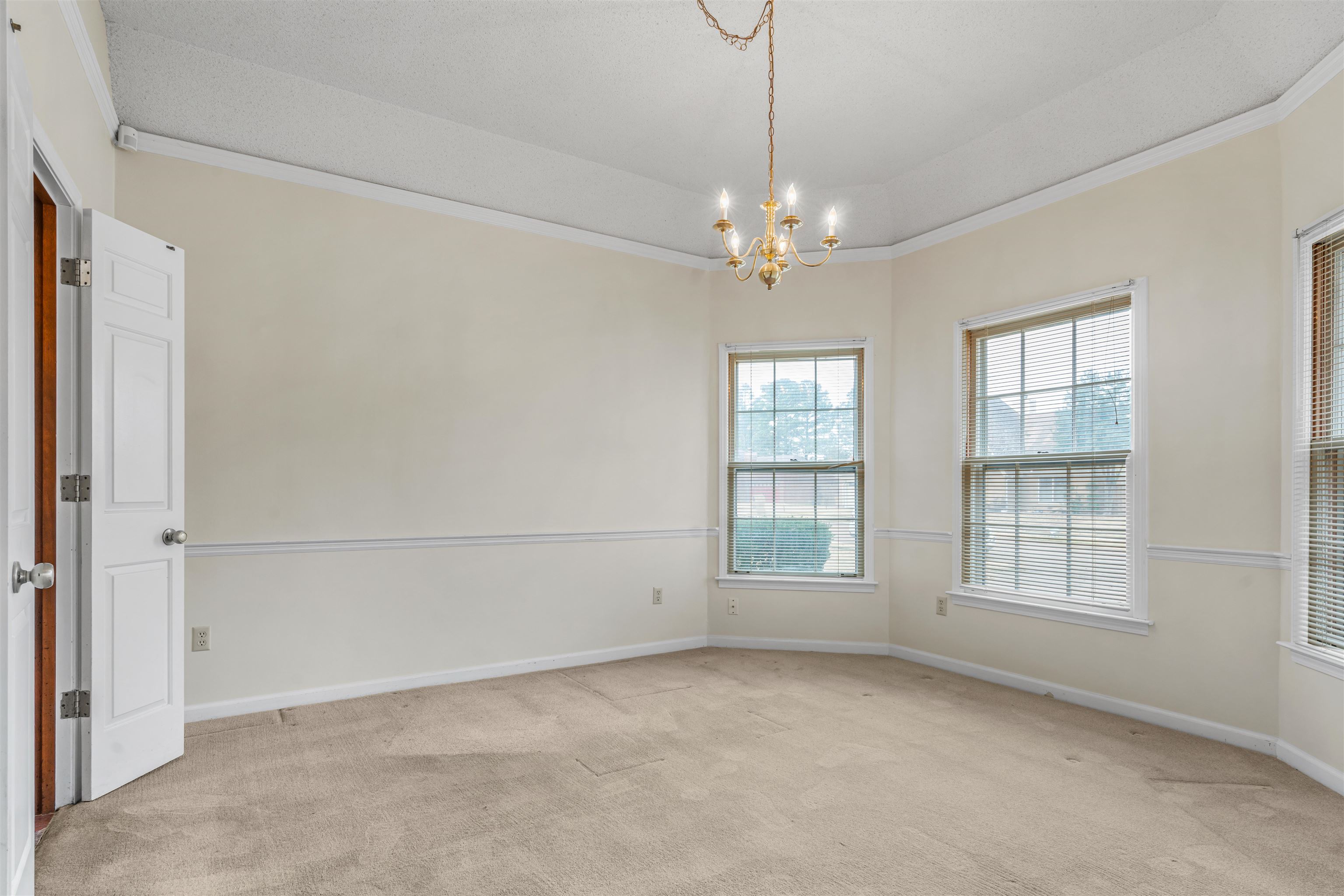 7087 Cutter Mill Road Memphis, TN 38141 - Photo 3 of 20 Coffered ceiling dining room with chandelier lighting, neutral colored carpet, and ornamental molding, bay window & double doors that lead to the kitchen.