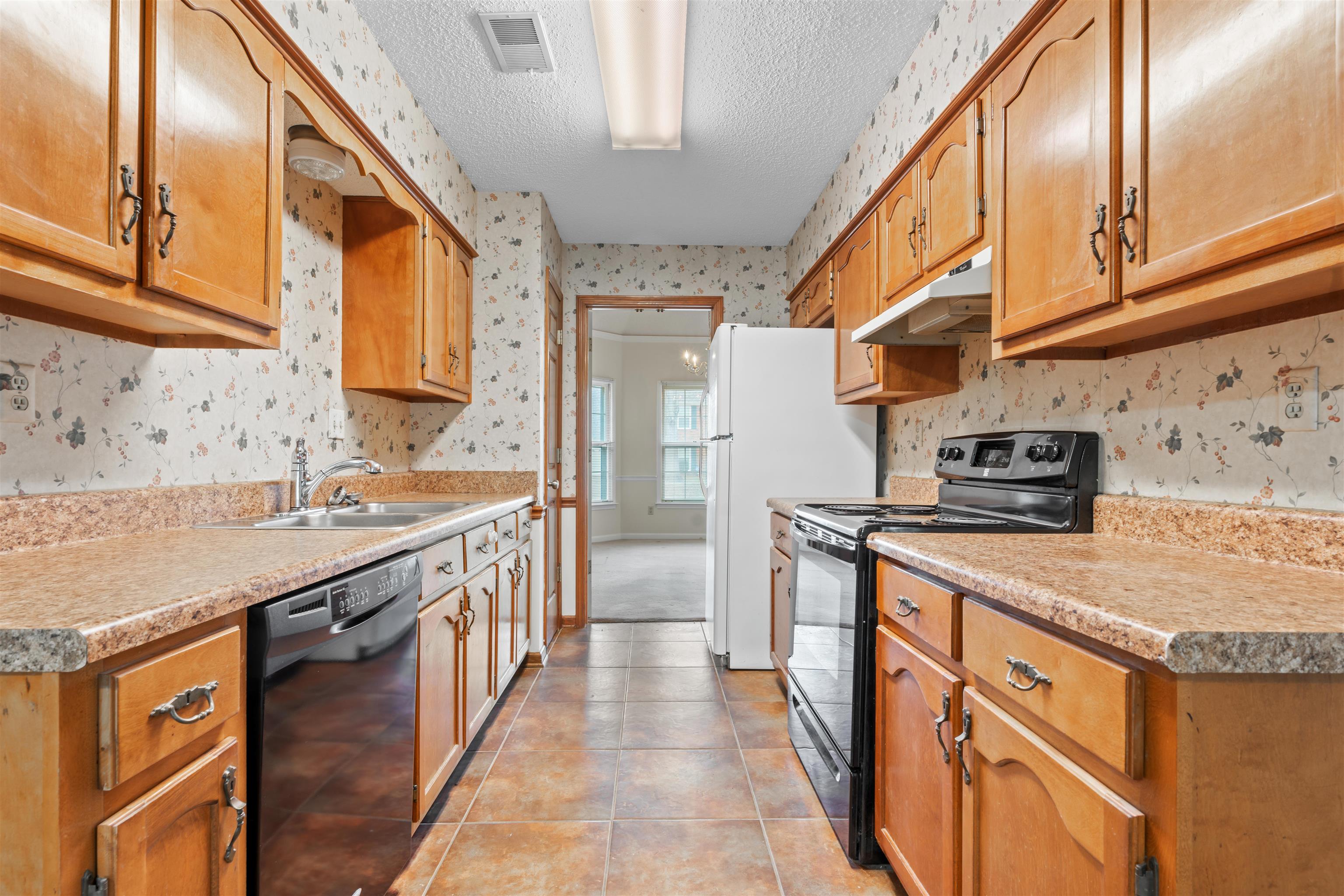 7087 Cutter Mill Road Memphis, TN 38141 - Photo 6 of 20 Kitchen with black appliances, sink, light tile patterned floors, and a textured ceiling