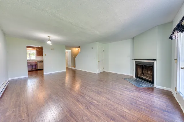 an empty room with wooden floor fireplace and windows