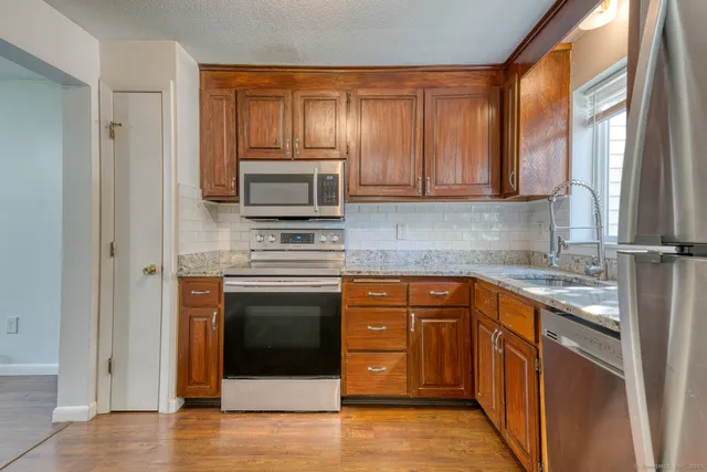 a kitchen with stainless steel appliances granite countertop a stove a sink and a microwave