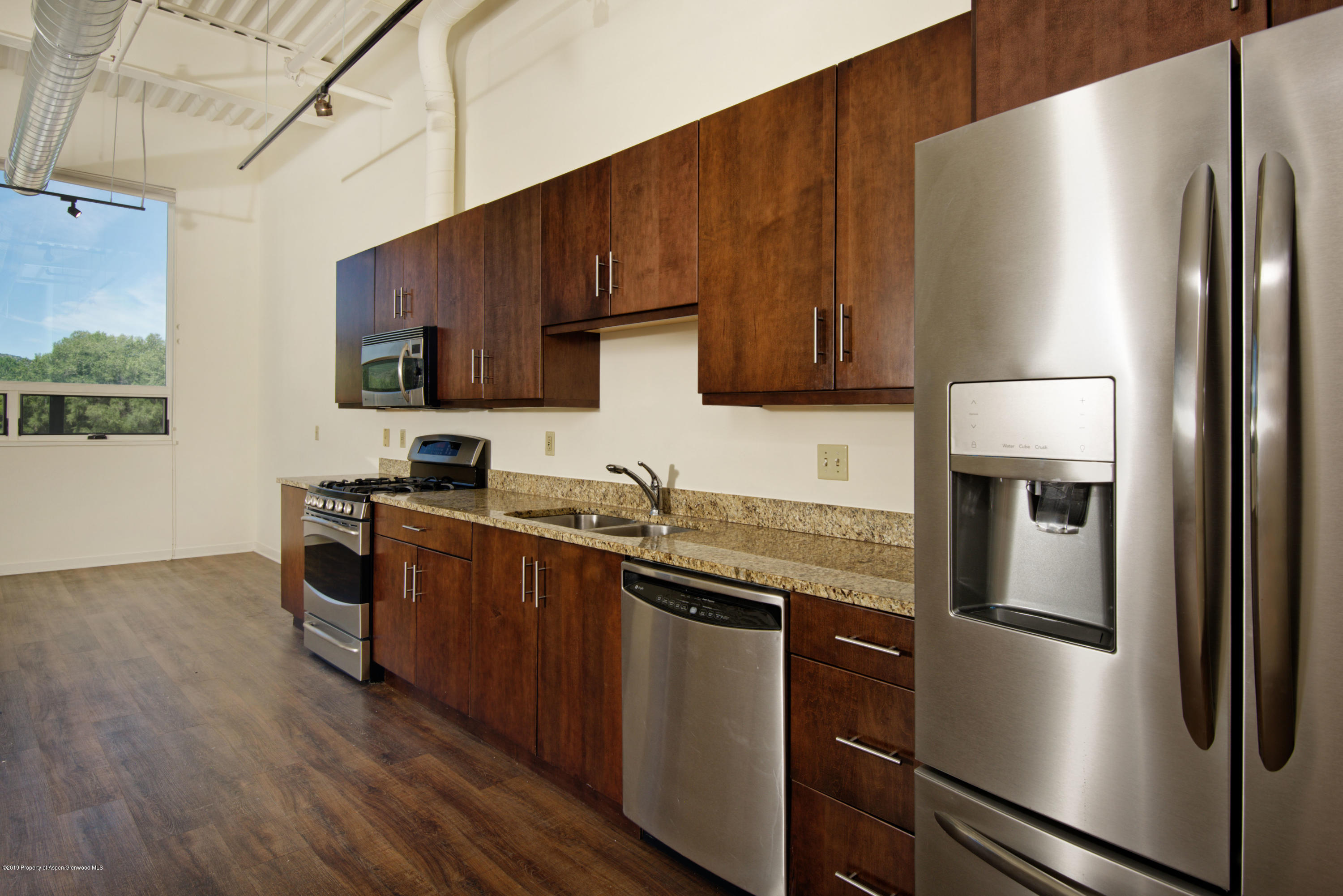 361 Robinson Street, Unit 202 Basalt, CO 81621 - Photo 6 of 29 a kitchen with stainless steel appliances granite countertop a refrigerator a stove and a sink with wooden floor
