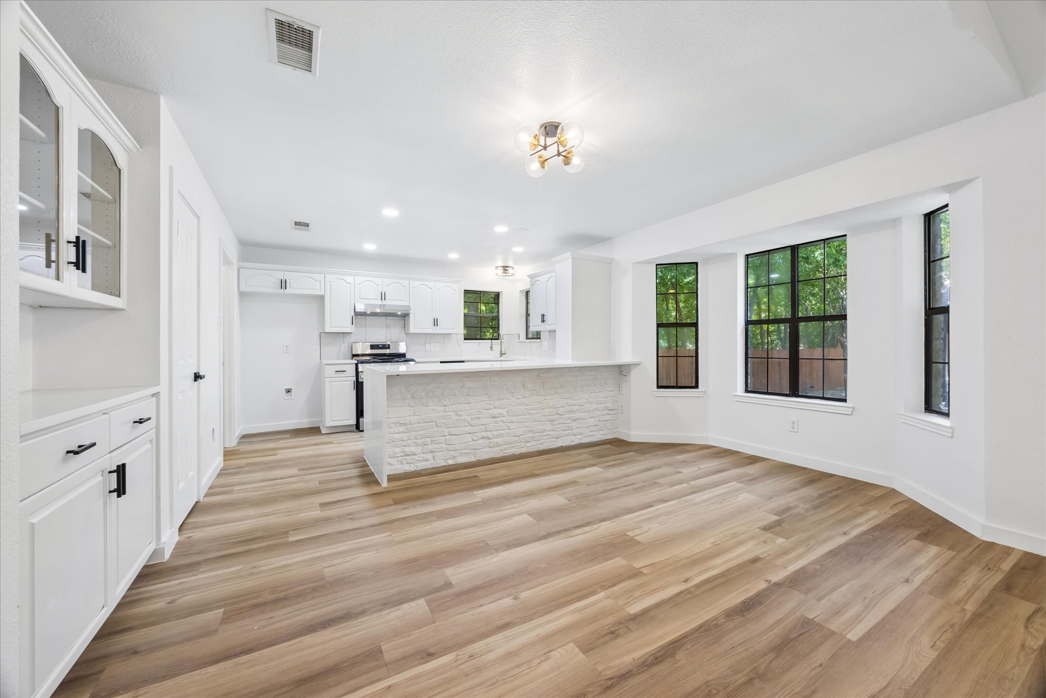 1706 Davis Street Taylor, TX 76574 - Photo 5 of 18 A naturally illuminated living space boasts wide plank flooring, with a seamless transition to the kitchen featuring modern appliances.